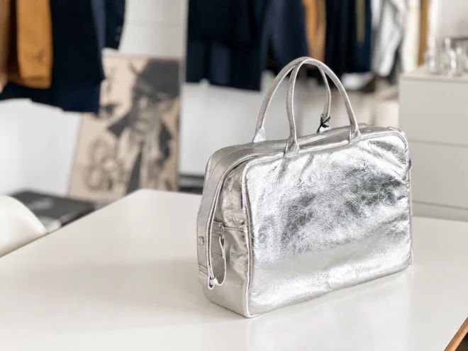 白いテーブルに置かれたシルバーのバッグ。普段使いしやすいコンパクトなデザイン