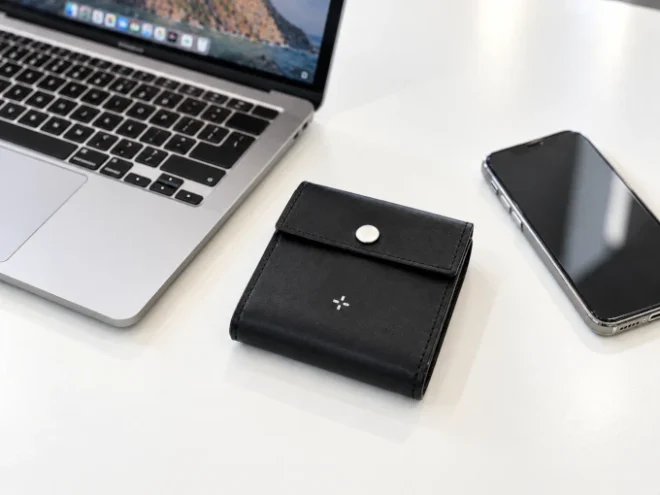 職場のデスクに置かれた黒革の小さい財布『パタンウォレット』。パソコンとスマートフォンの間にもすっきり収まるコンパクトな革財布。